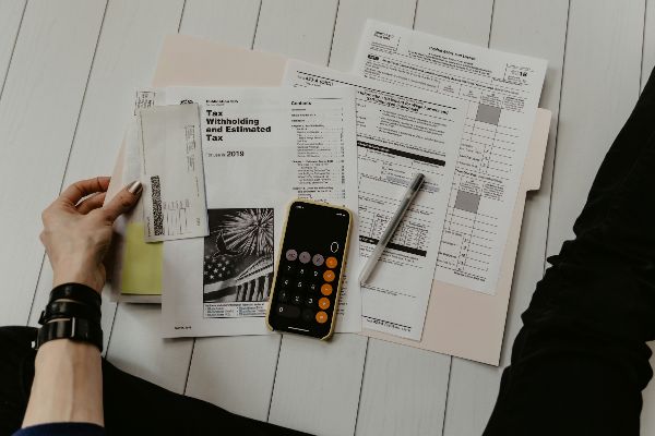 Tax forms, a calculator and a pen spread across a desk