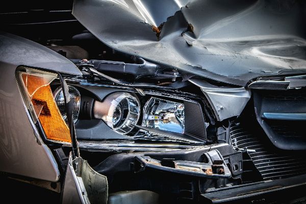 Close-up of a car's crushed hood and broken headlight after a collision